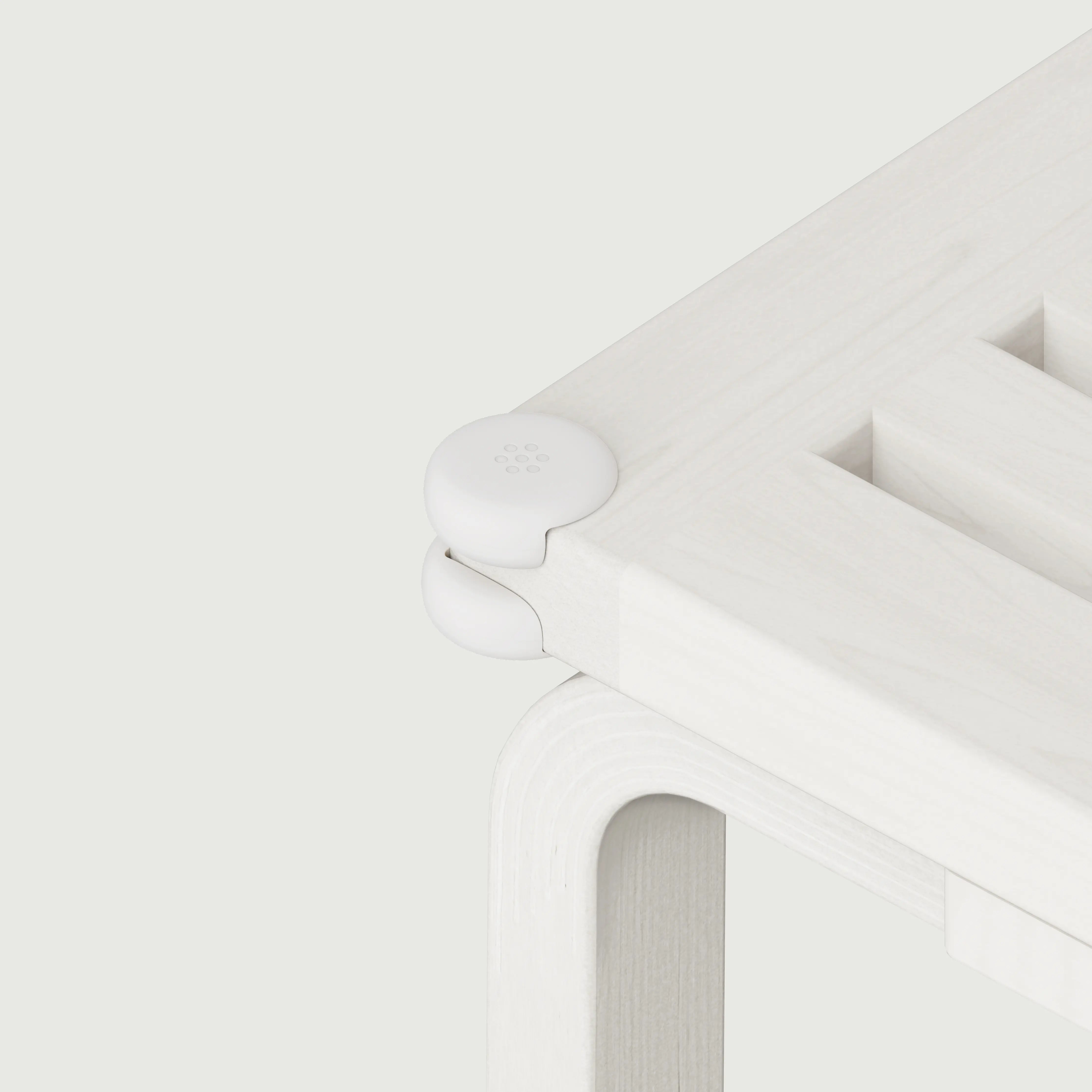 Pom Corner Protector — soft silicone babyproofing guard for sharp furniture corners on a white bench